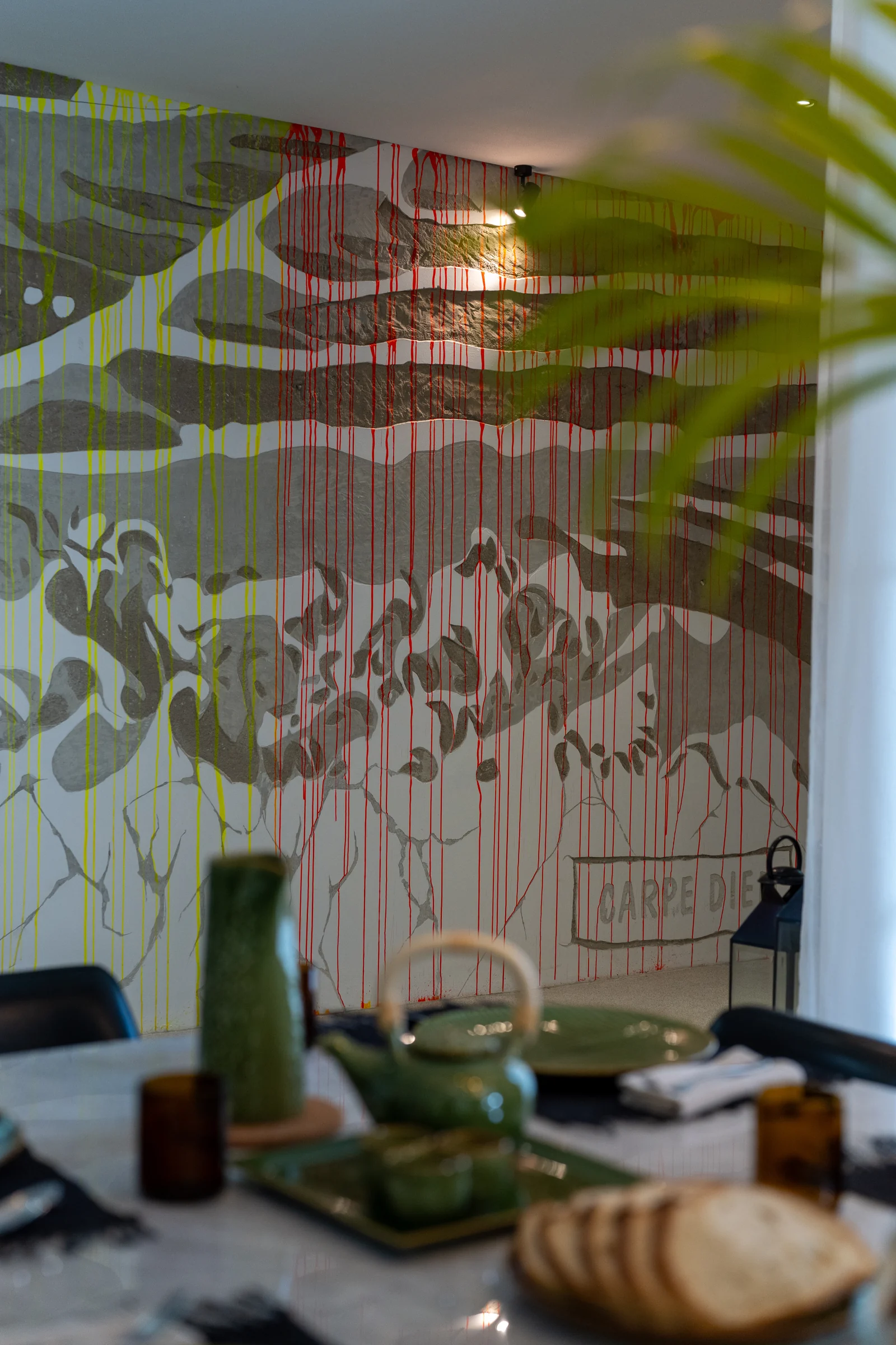 A view through greenery toward the dining table and contemporary art in the villa
