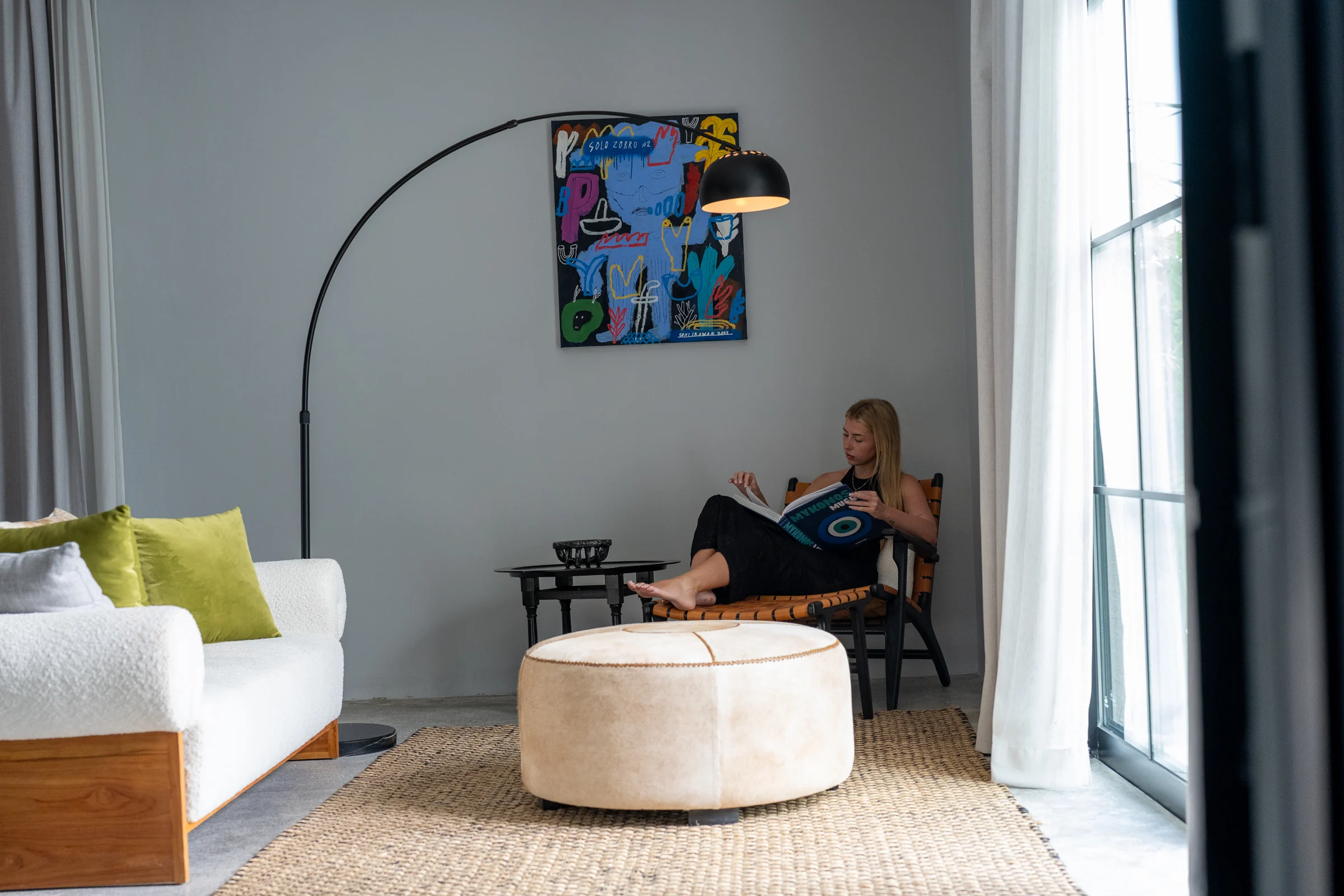 A guest reading in a bedroom seating area beside the window