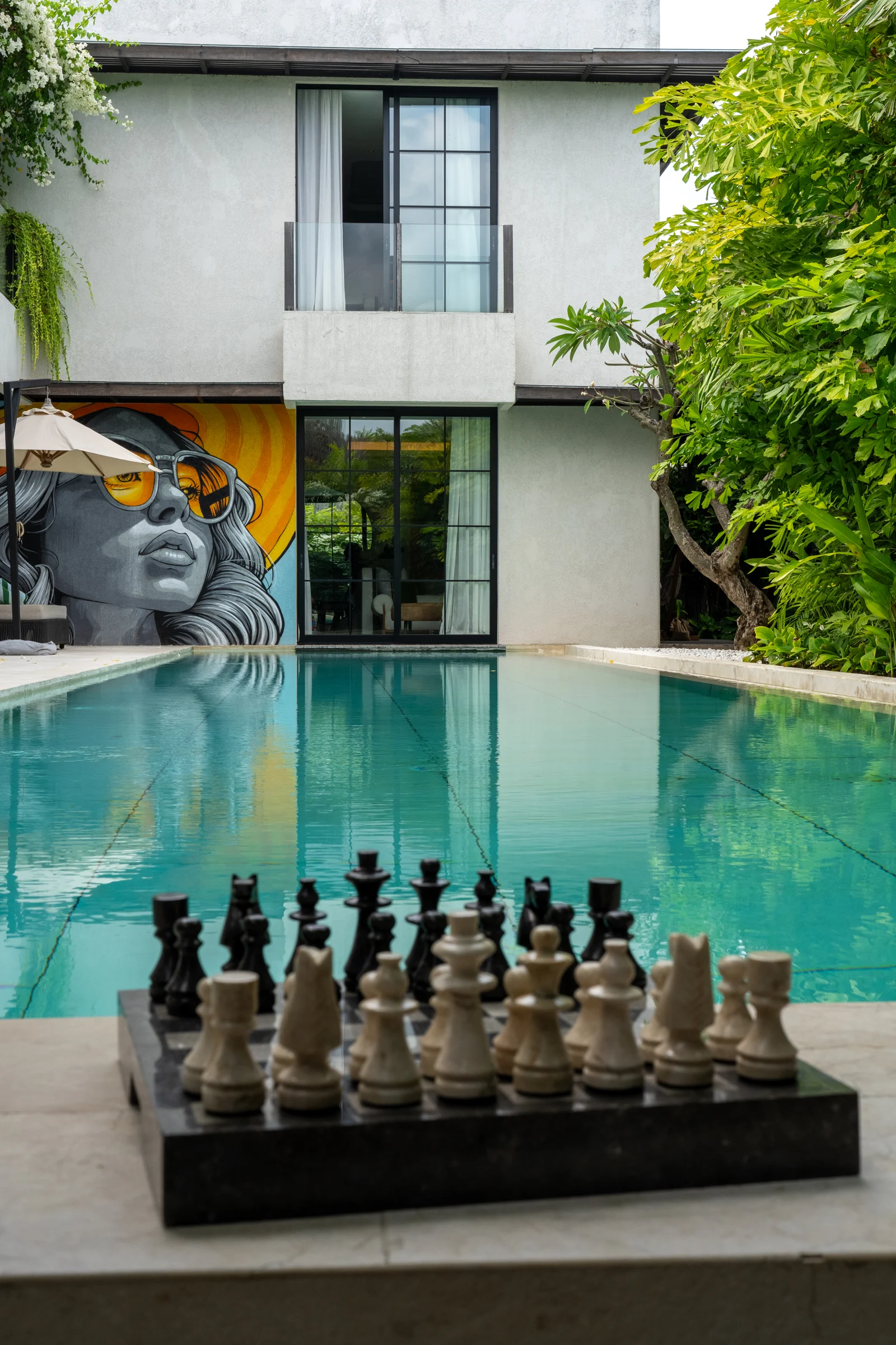 A chessboard beside the private pool, with the villa’s mural beyond