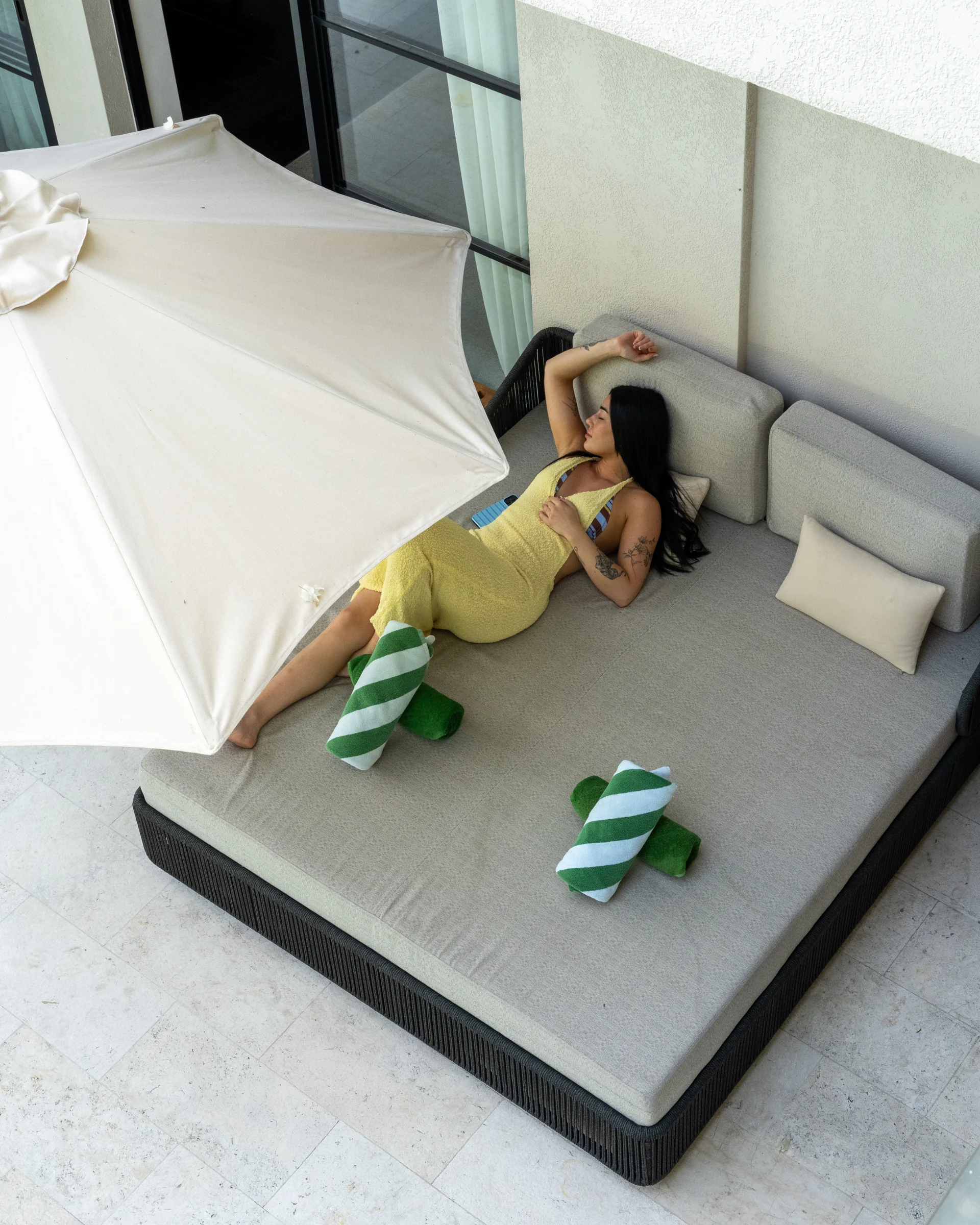 A guest resting on a daybed beside a bedroom and the private pool